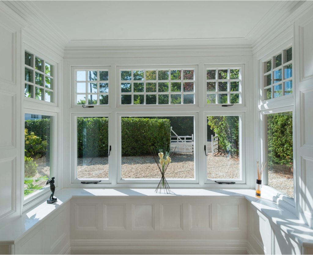 Double glazed window overlooking a stone driveway with a gate and bushes