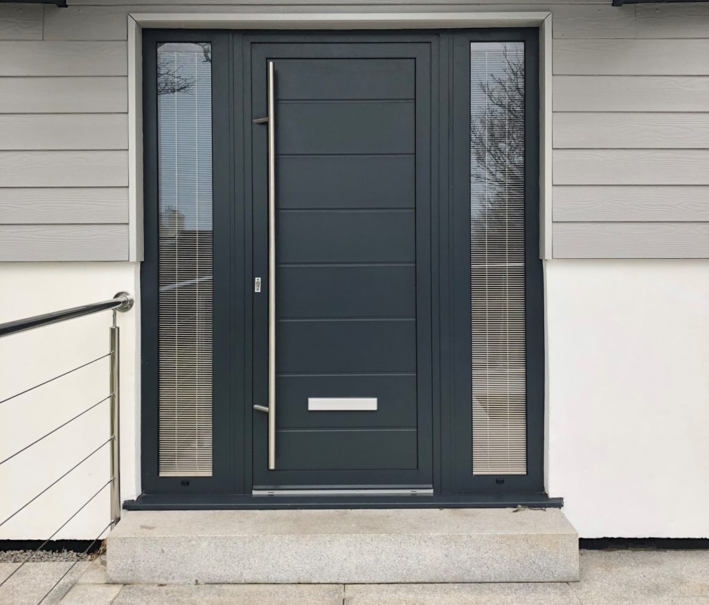 Modern front door with two narrow side windows. It features a sleek handle and a minimalist mail slot.